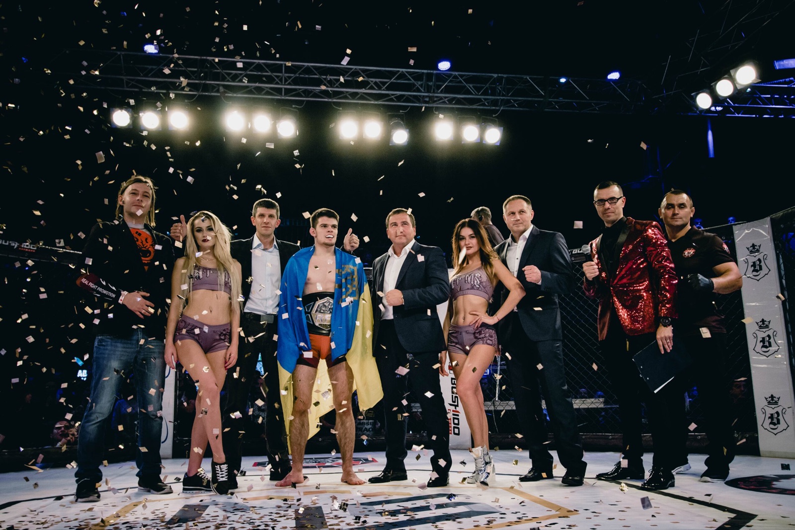 A champion with a belt and the Ukrainian flag poses with the team and organizers.