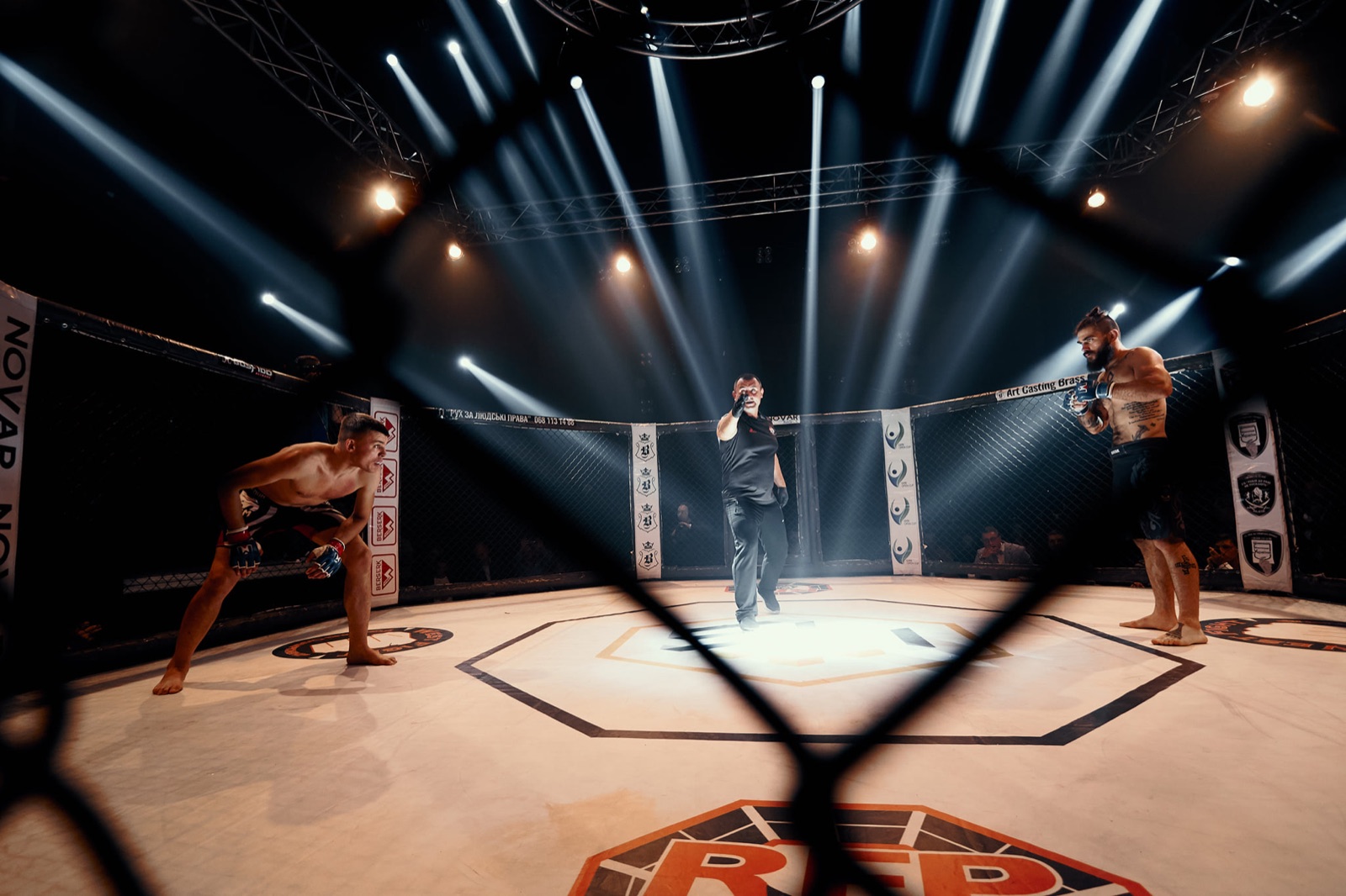 Two fighters begin an exchange under beams of arena light.